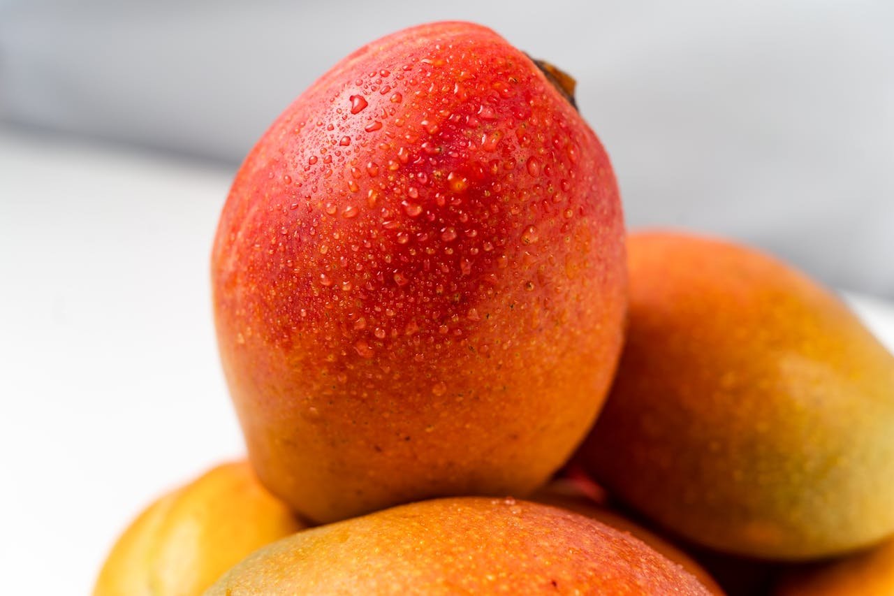 A vibrant close-up of fresh mangoes with water droplets emphasizing freshness and juiciness.